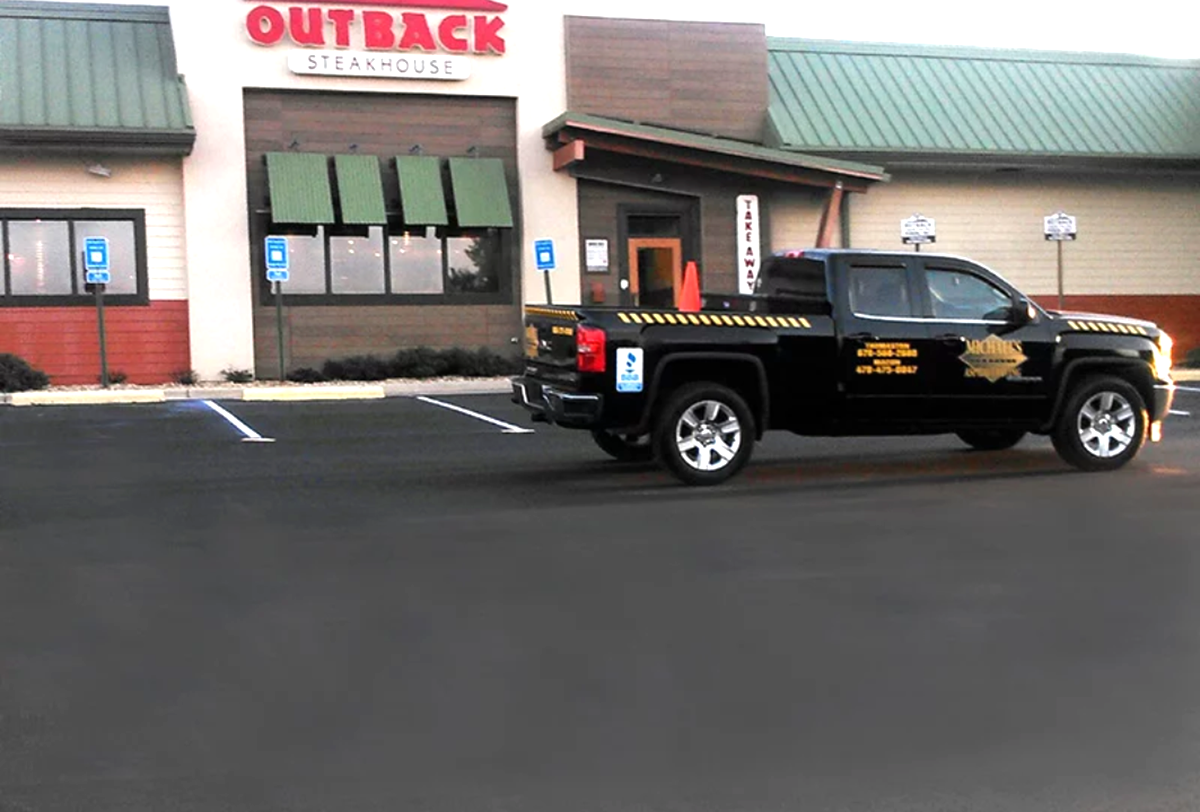 A black truck is parked in front of a restaurant