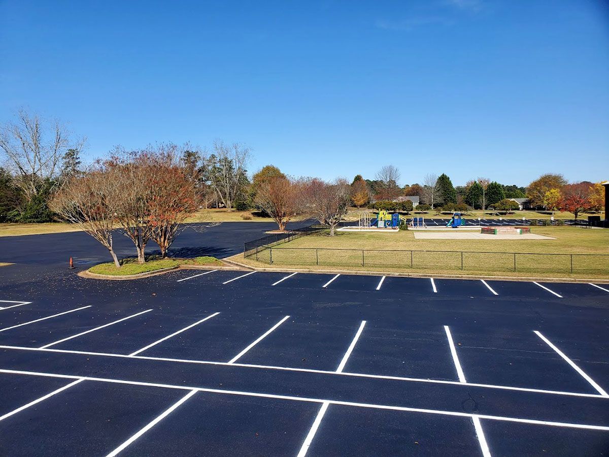 A newly paved parking lot with a playground in the background
