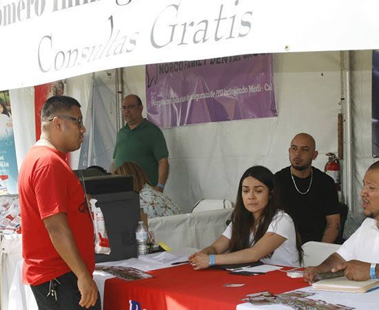 A man in a red shirt stands in front of a sign that says 