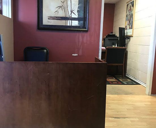 A wooden desk in a room with a picture on the wall above it