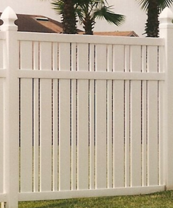 A white vinyl privacy fence with a decorative design featuring alternating vertical slats, set against a lawn and trees.
