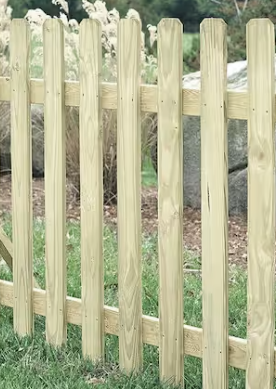 A close-up of a light-colored wooden picket fence with angled tops set against a grassy, outdoor background.