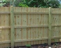 A new wooden privacy fence with vertical pickets, three horizontal support rails, and sturdy square posts.