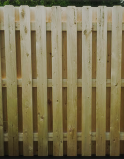 A light-colored wooden fence with vertical pickets arranged in a side-by-side pattern against a flat backing board.
