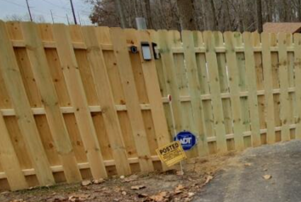 A wooden fence with an ADT security sign and a yellow 