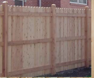 A close-up view of a new, light-colored wooden privacy fence with vertical boards and three horizontal support rails.