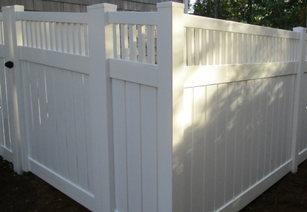 A white vinyl privacy fence with a decorative lattice top, shown from a corner angle outdoors.
