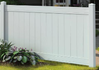 A white vinyl privacy fence panel with decorative accent rails installed in a green yard with a small shrub.