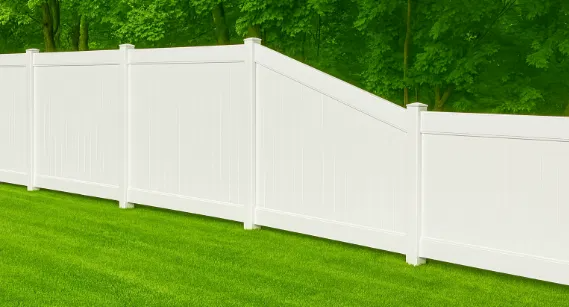 A white vinyl fence with a stepped section transitions between heights against a backdrop of lush green trees and lawn.
