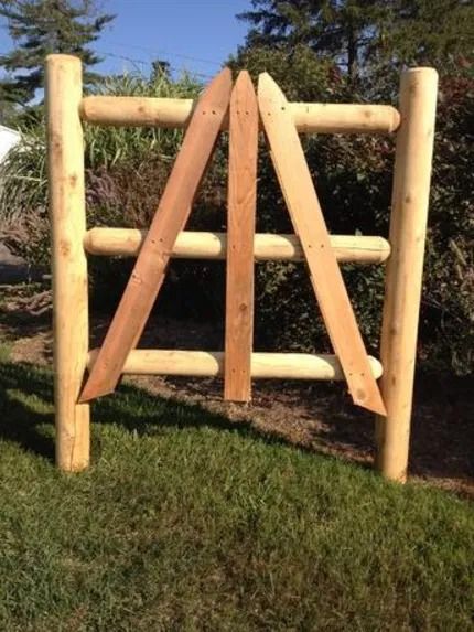 A wooden fence section with a central design made of three pointed, angled boards between two upright posts.