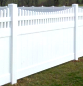 A white vinyl privacy fence with a scalloped picket top section set against a grassy background.