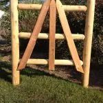 A wooden gate featuring three horizontal rails and a central vertical support framed by two angled boards.