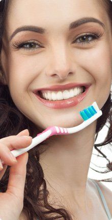 Woman holding a toothbrush and showing her white teeth