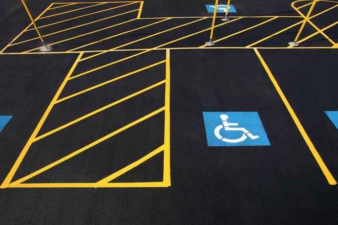 Accessible parking spaces with yellow diagonal striping and blue wheelchair symbols on black pavement