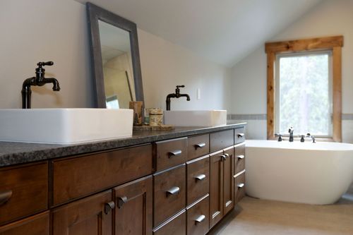 Modern bathroom with double vanity, dark wood cabinets, and a freestanding white tub by a window
