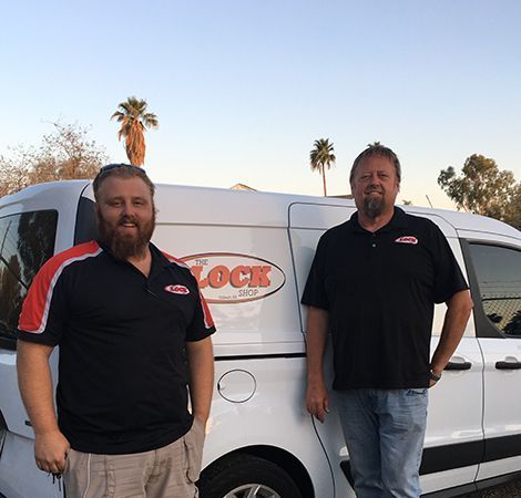 Two men are standing in front of a white van that says lock on it.