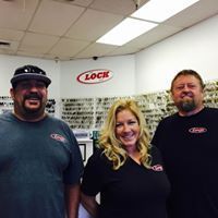 Three people are posing for a picture in a locksmith shop.