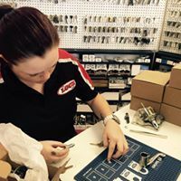 A woman is sitting at a table in a store working on a piece of equipment.