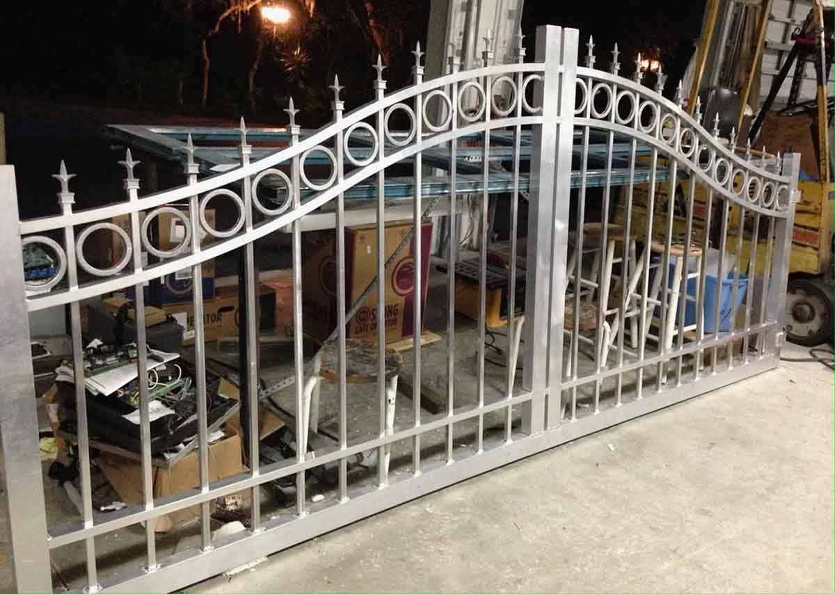 A wrought iron gate is sitting on the ground in front of a forklift.