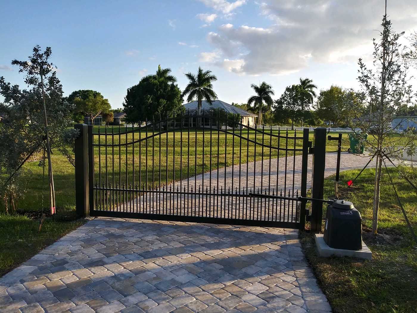 A driveway with a gate and a brick walkway