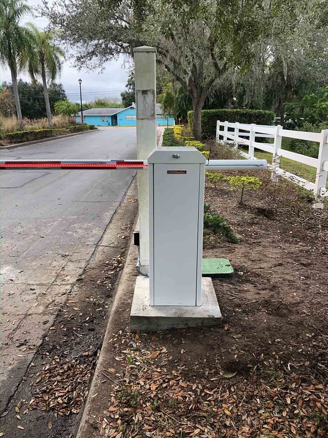A white barrier is sitting on the side of a road next to a white fence.
