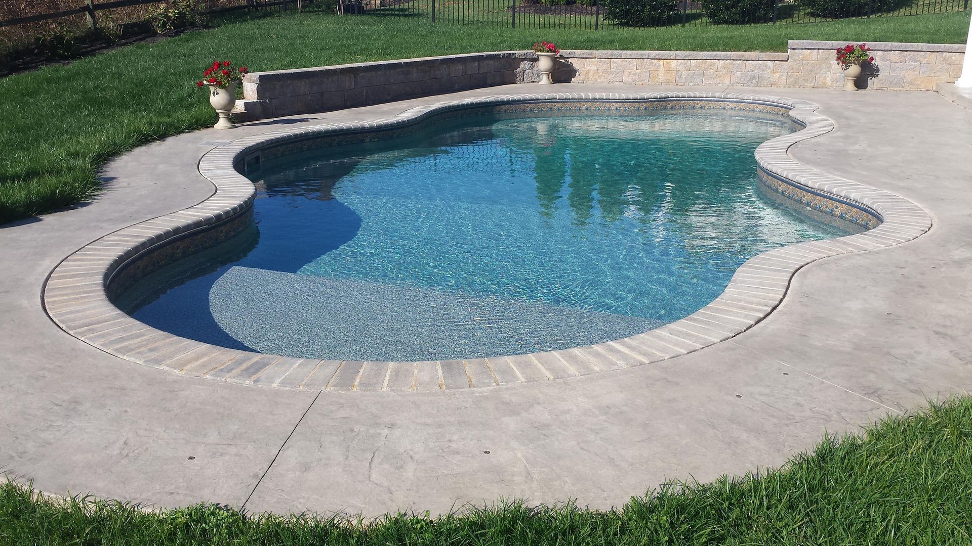 A large swimming pool is sitting on top of a concrete patio in a backyard.
