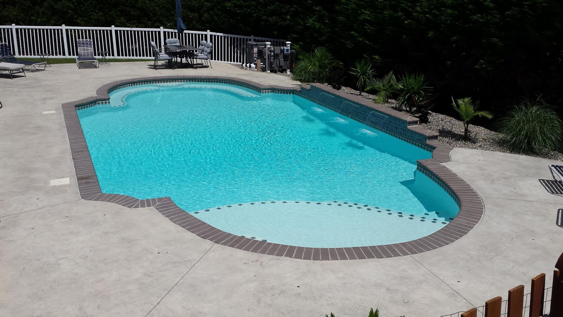 A large swimming pool with a white fence around it