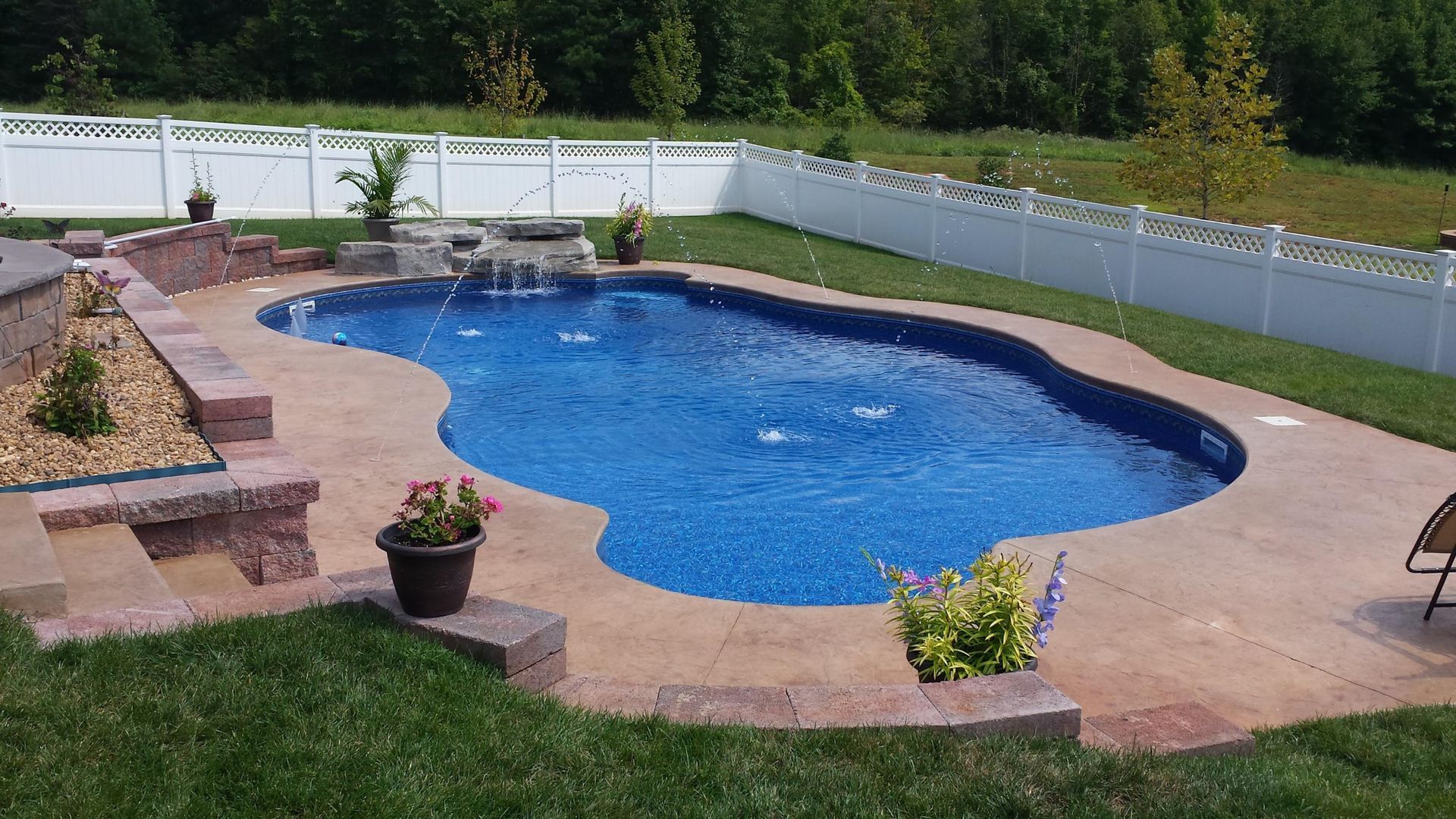 A large swimming pool with a waterfall in the backyard.