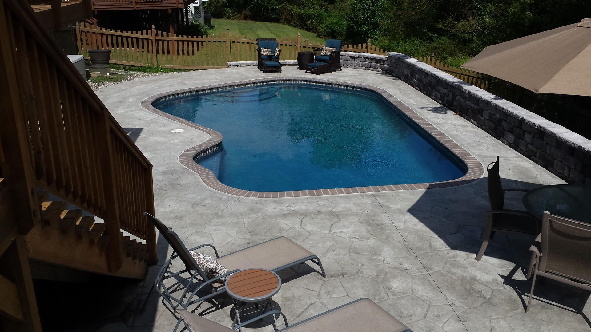 A large swimming pool is surrounded by chairs and umbrellas