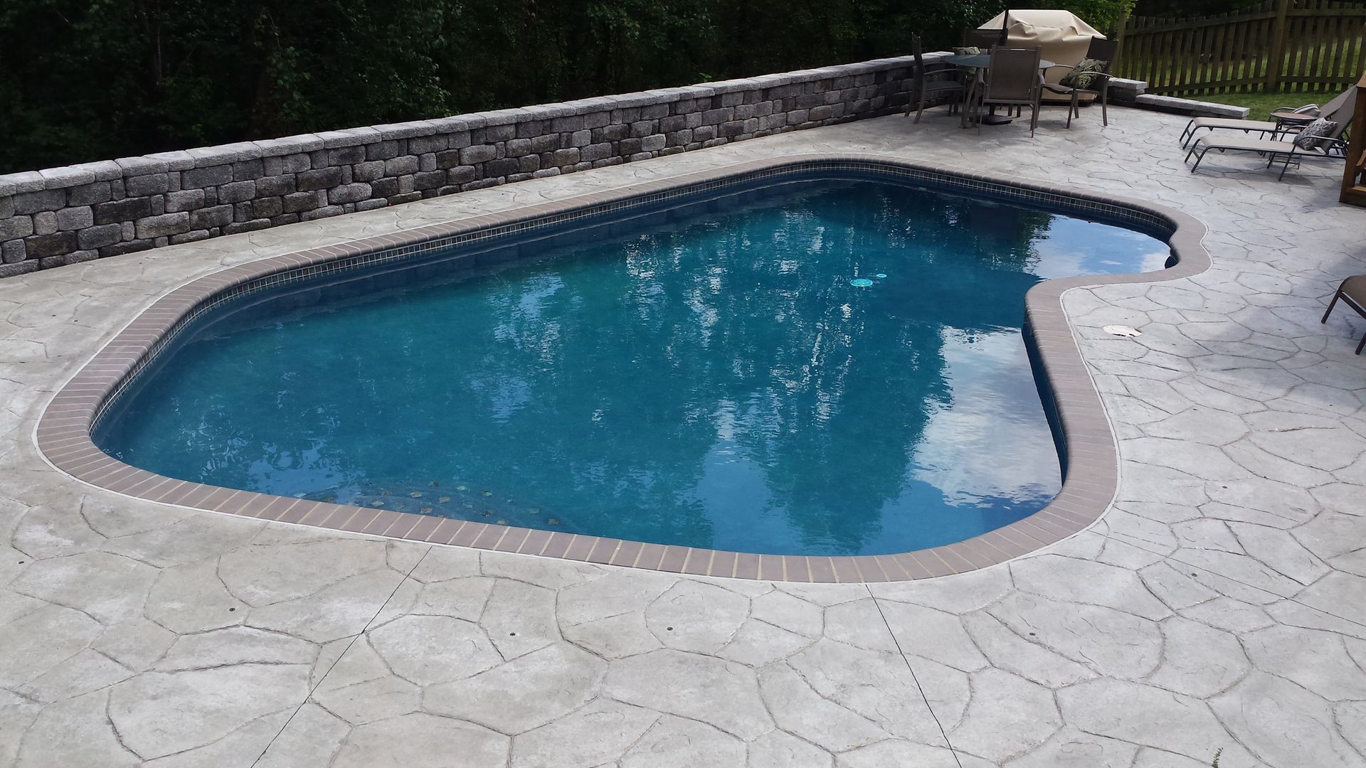 A large swimming pool with a stone wall surrounding it