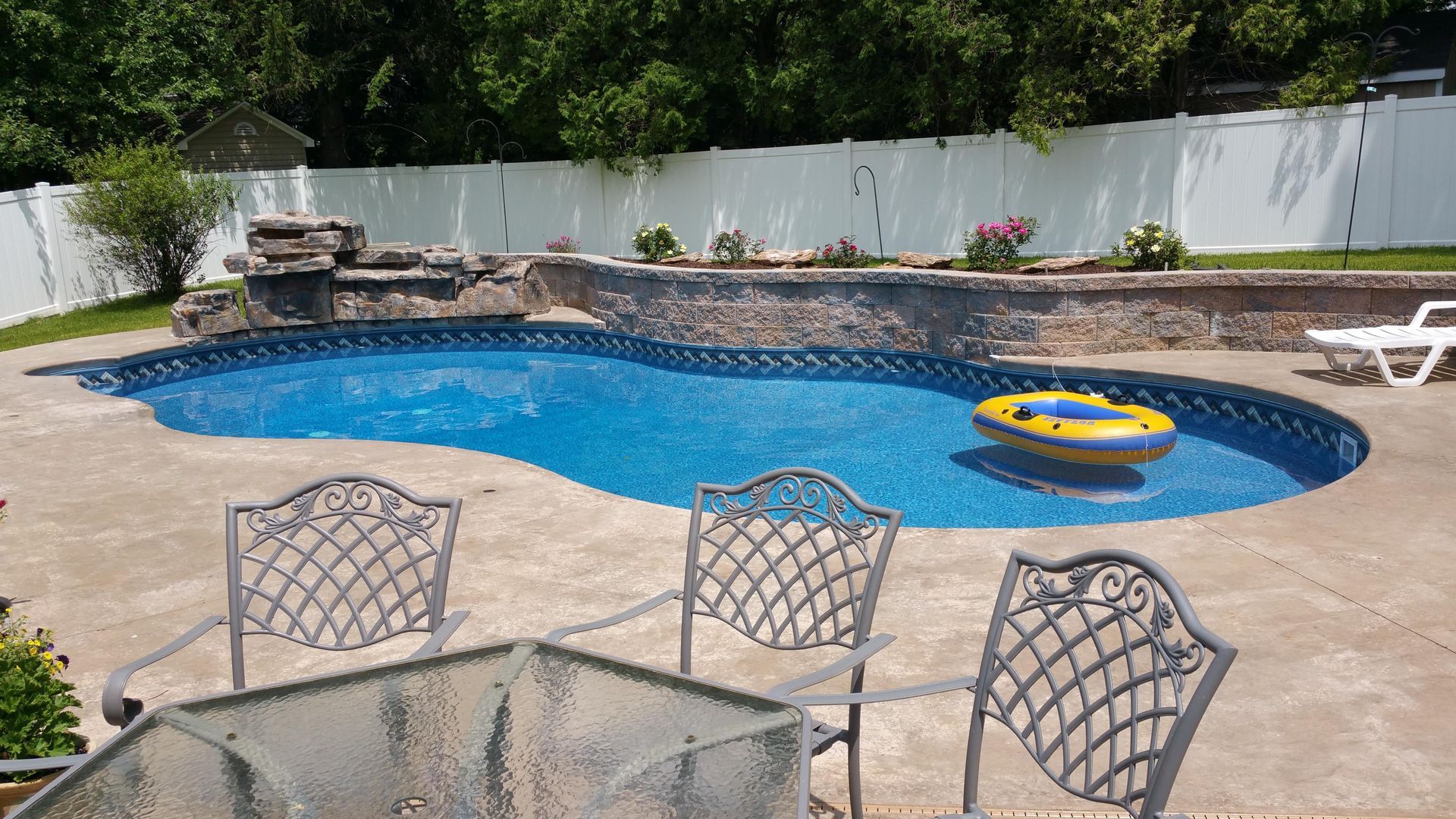 A large swimming pool with a table and chairs in front of it.