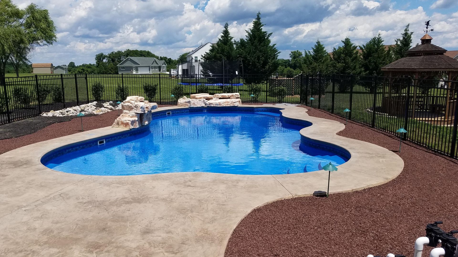 A large swimming pool with a gazebo in the backyard.
