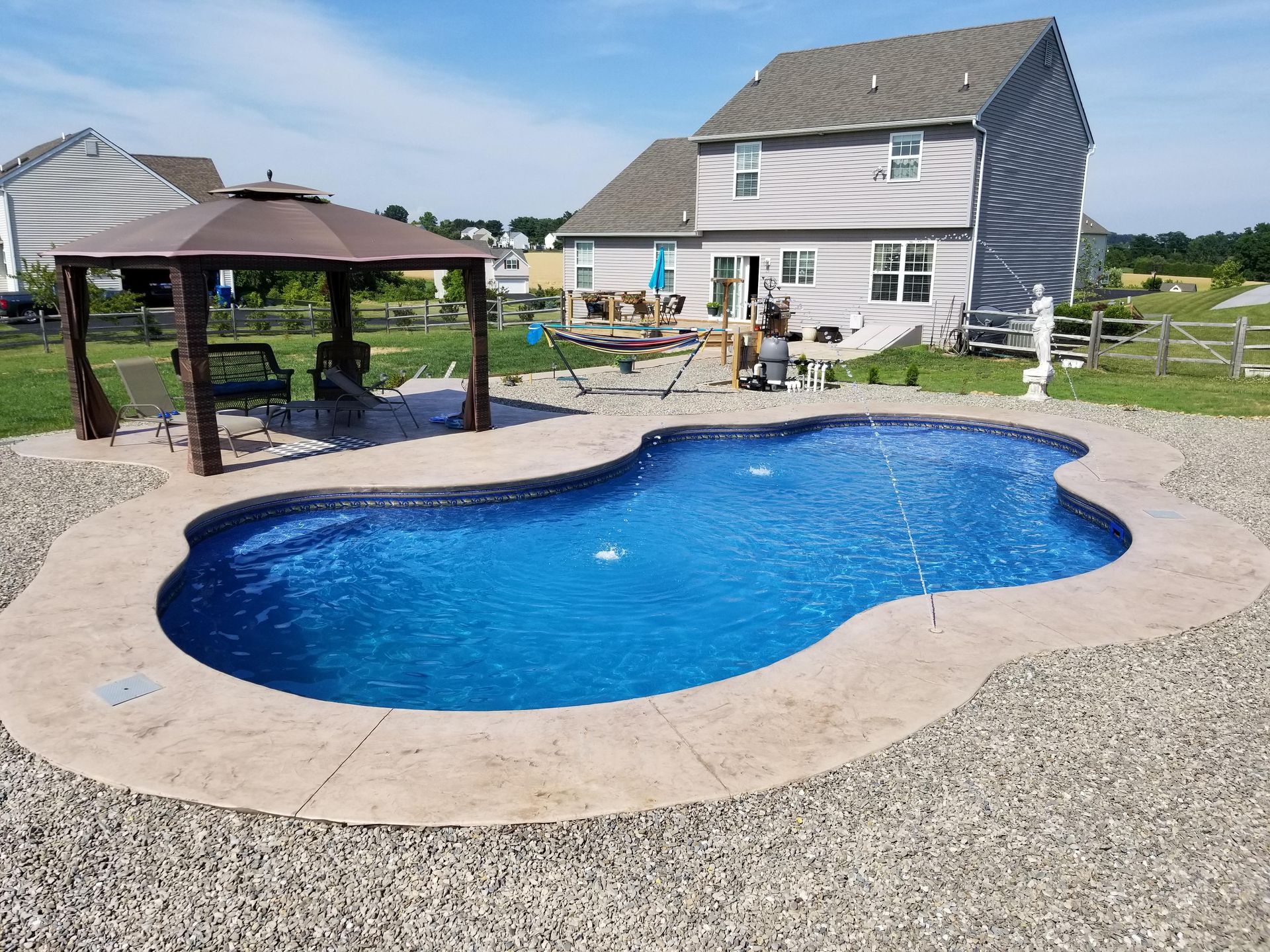 A large swimming pool with a gazebo in front of a house