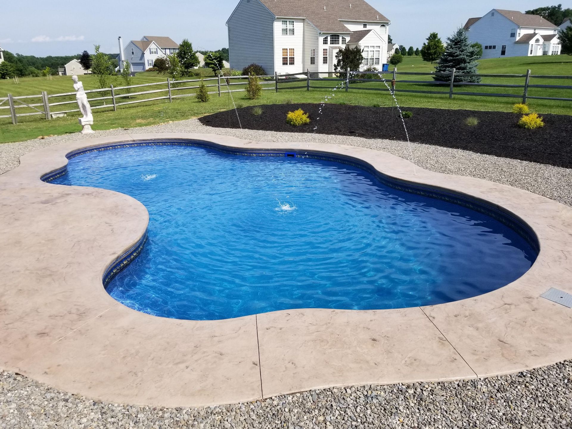 A large swimming pool with a house in the background