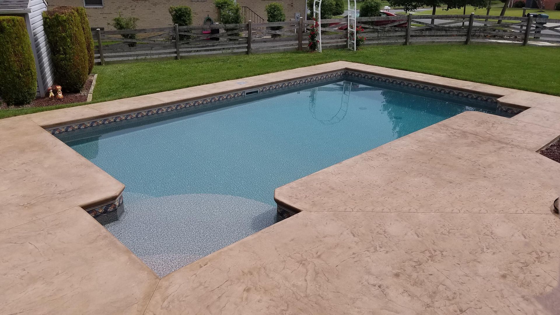 A large swimming pool is sitting on top of a concrete patio in a backyard.