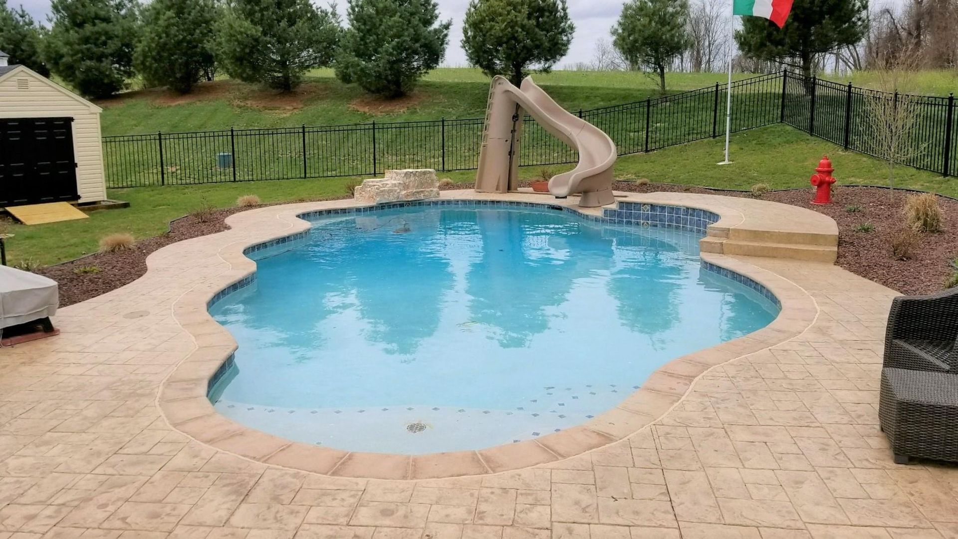 A large swimming pool with a slide in the backyard.