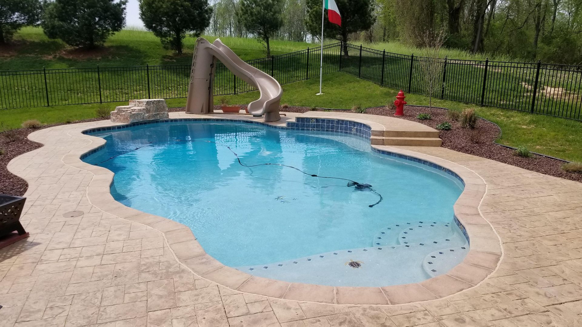 A large swimming pool with a slide in the backyard.