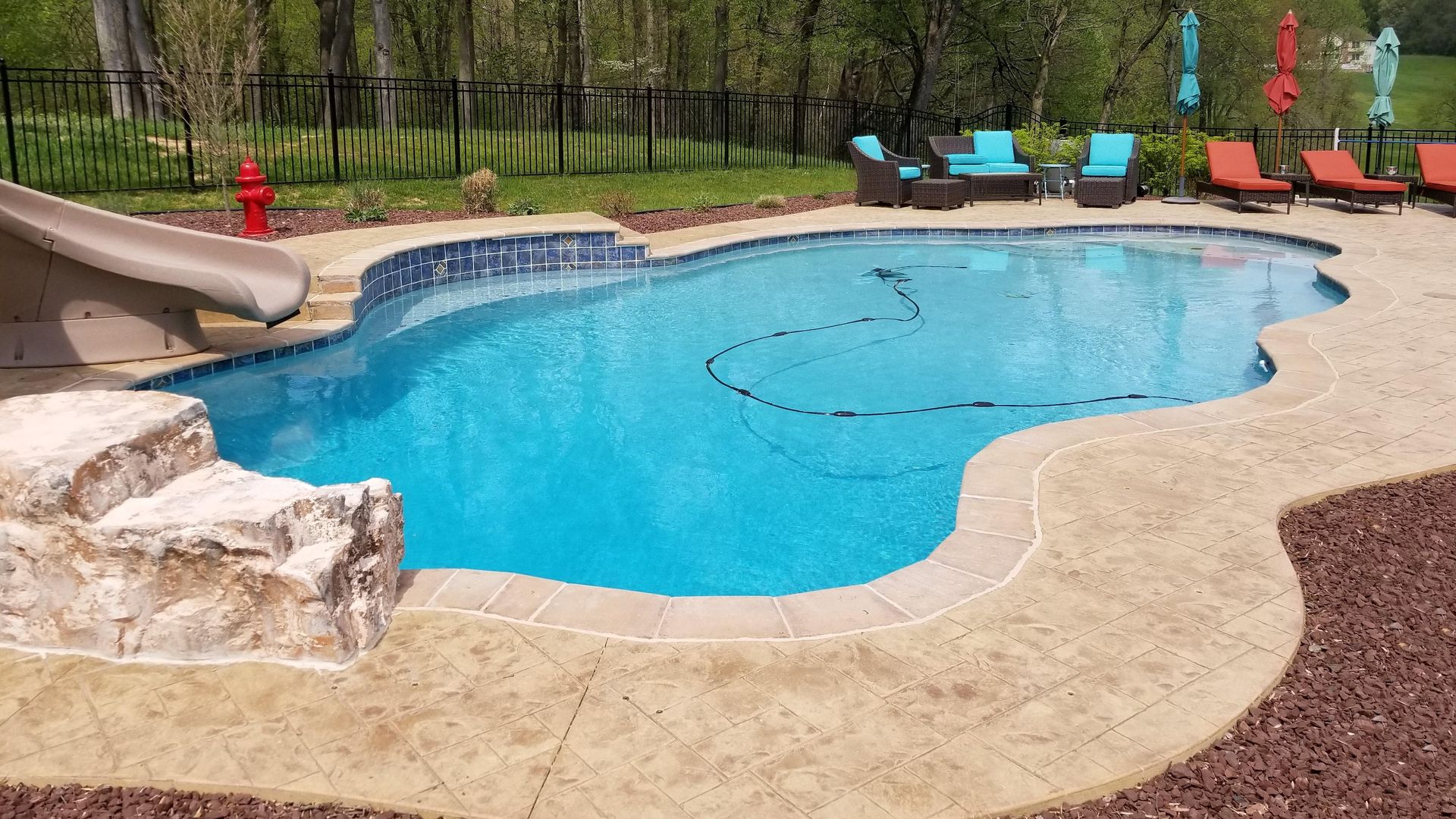 A large swimming pool with a slide in the backyard