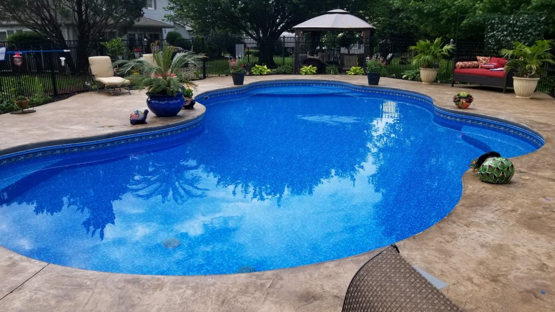 A large blue swimming pool with a gazebo in the background