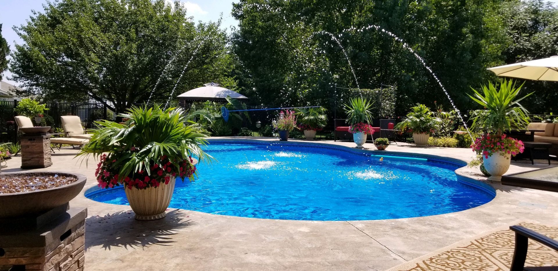 A large swimming pool with a fountain in the middle of it in a backyard.