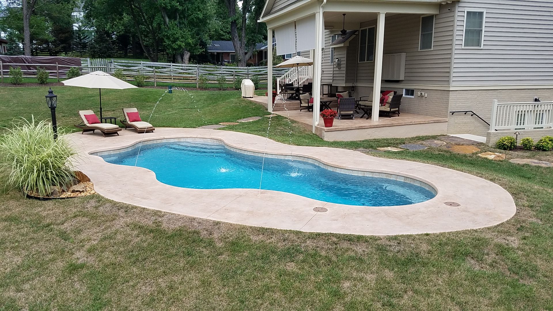 A large swimming pool is in the backyard of a house.
