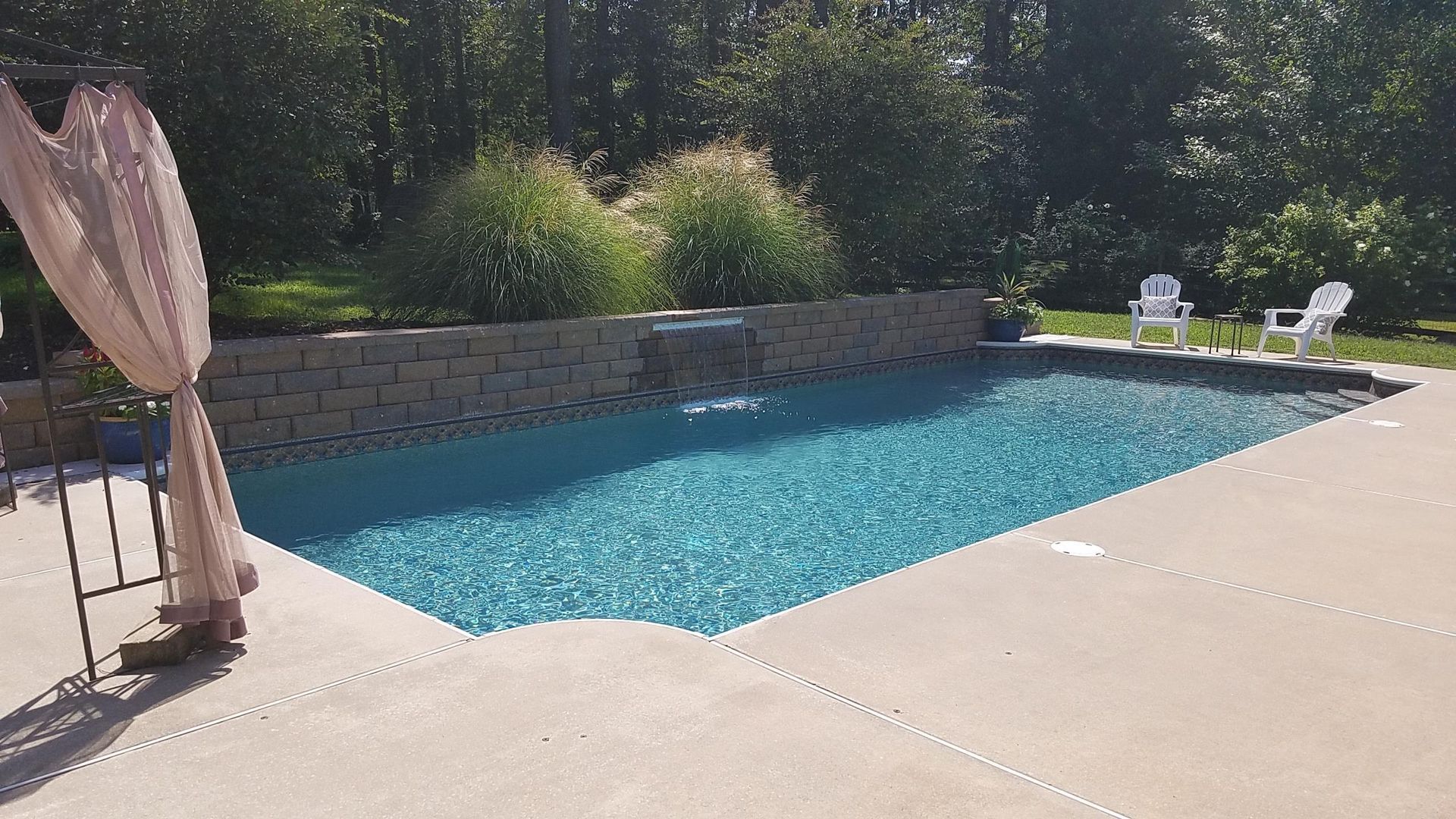 A large swimming pool with a canopy and chairs around it.