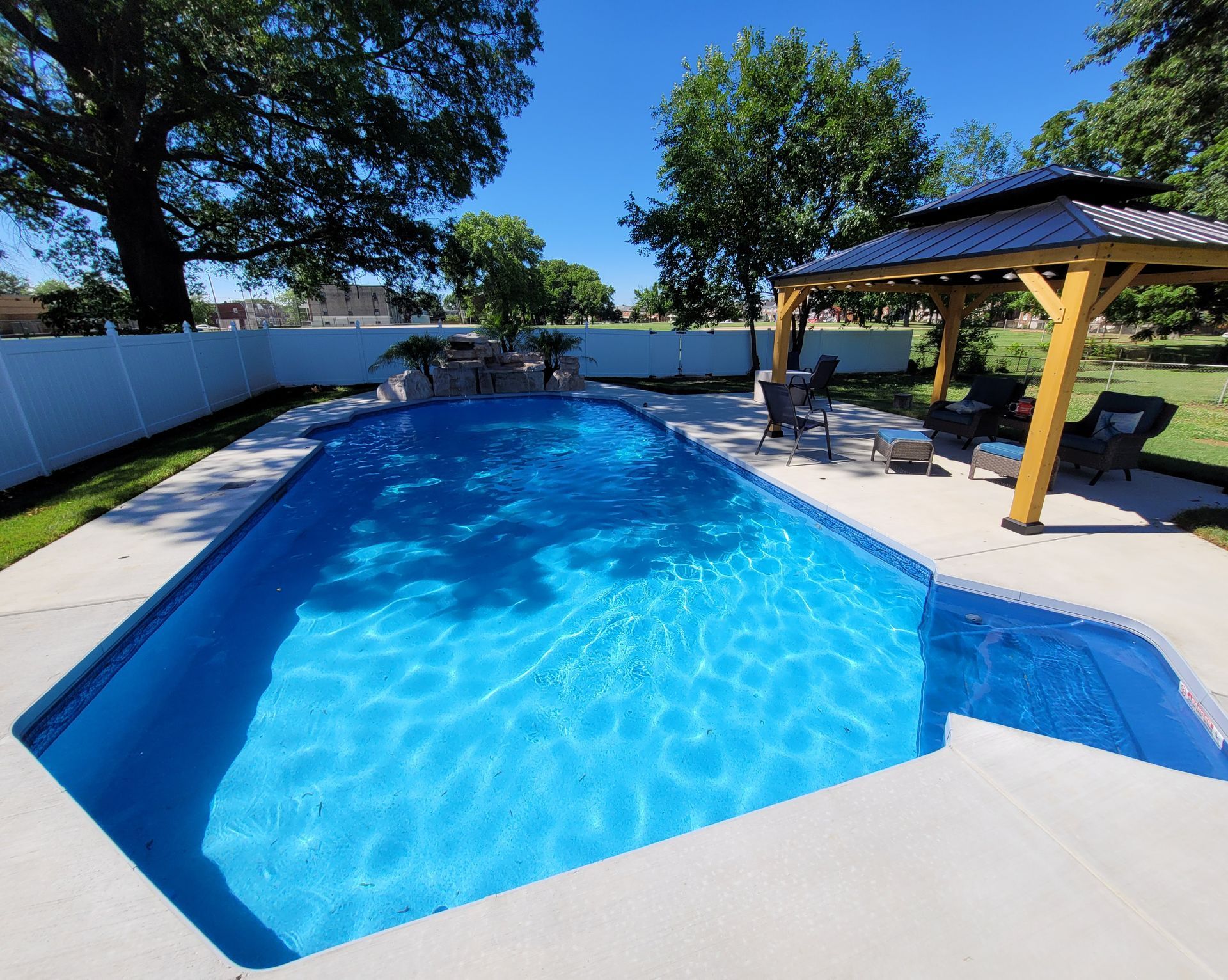 A large swimming pool with a gazebo in the backyard