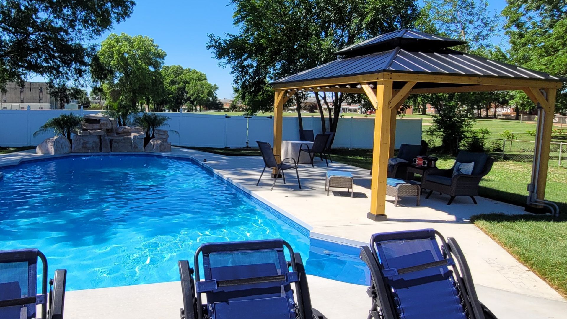 A large swimming pool with a gazebo in the backyard