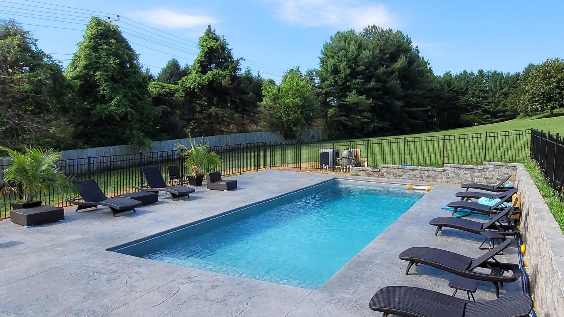 A large swimming pool surrounded by chairs and trees