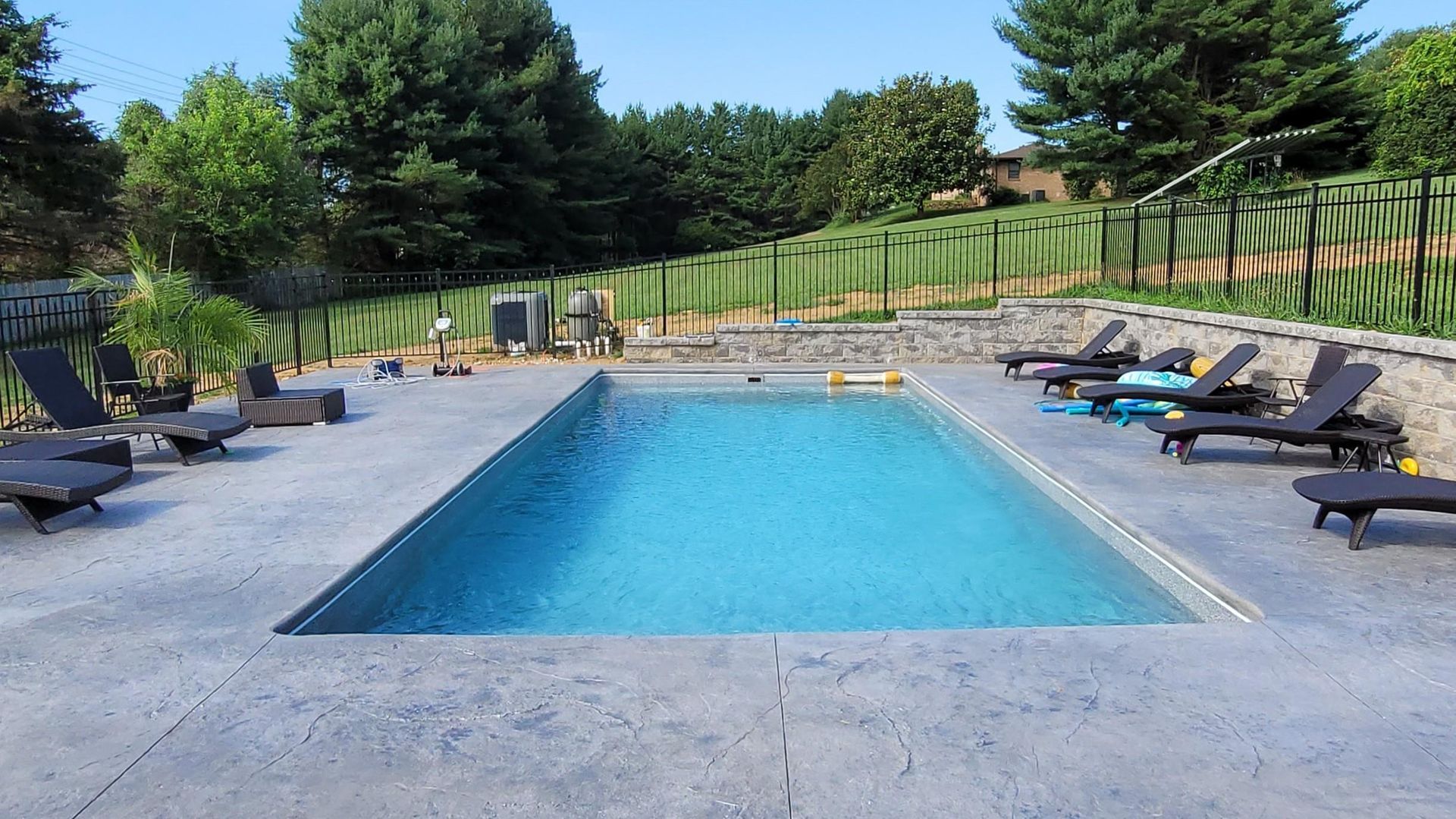 A large swimming pool surrounded by chairs and trees