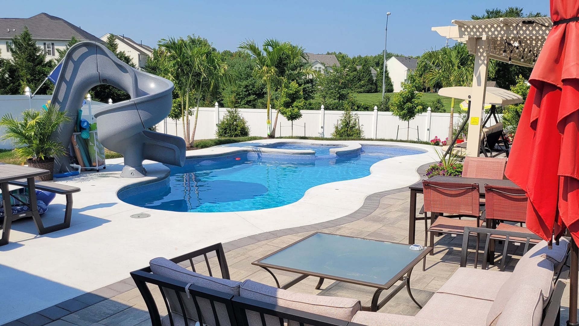 A large swimming pool with a water slide in the backyard.