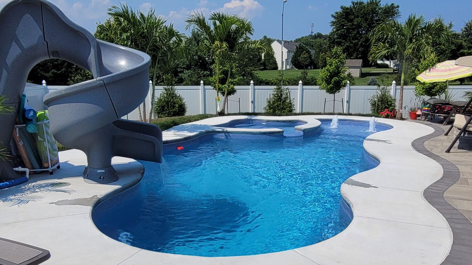 A large swimming pool with a slide in the backyard