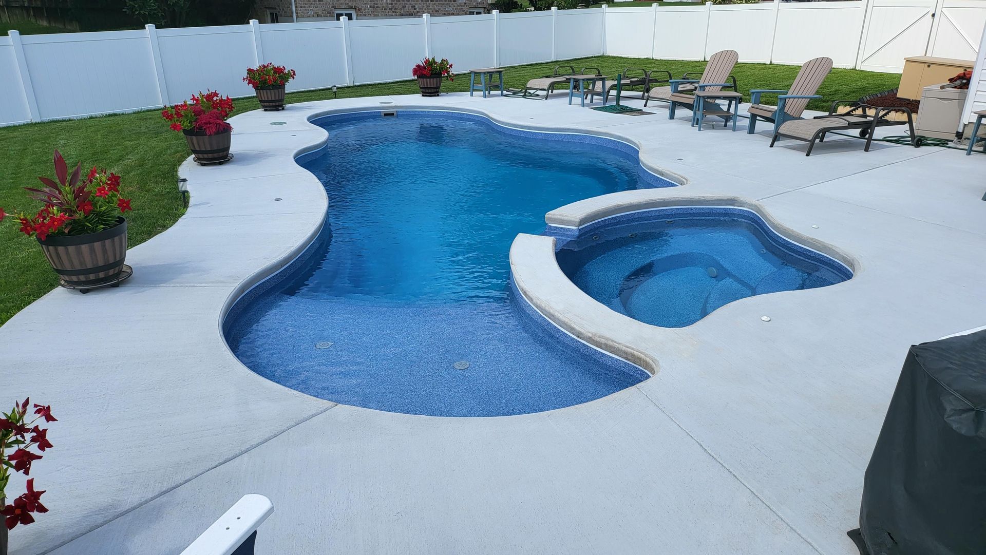 A large swimming pool with a hot tub in the backyard.