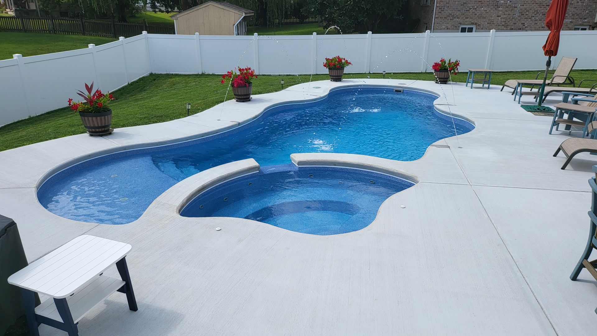 A large swimming pool with a hot tub in the backyard.